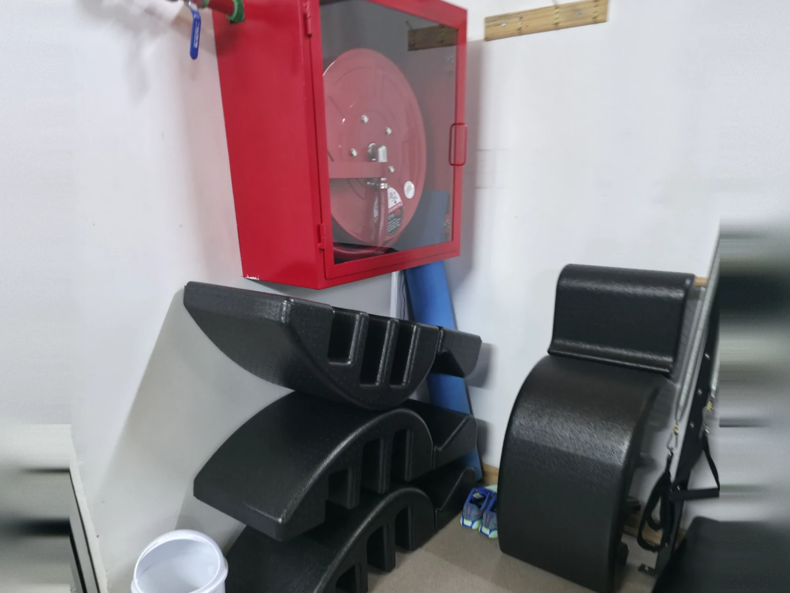 Spine Corrector negros apilados en el suelo de una esquina de la sala de pilates, antes de instalar los soportes